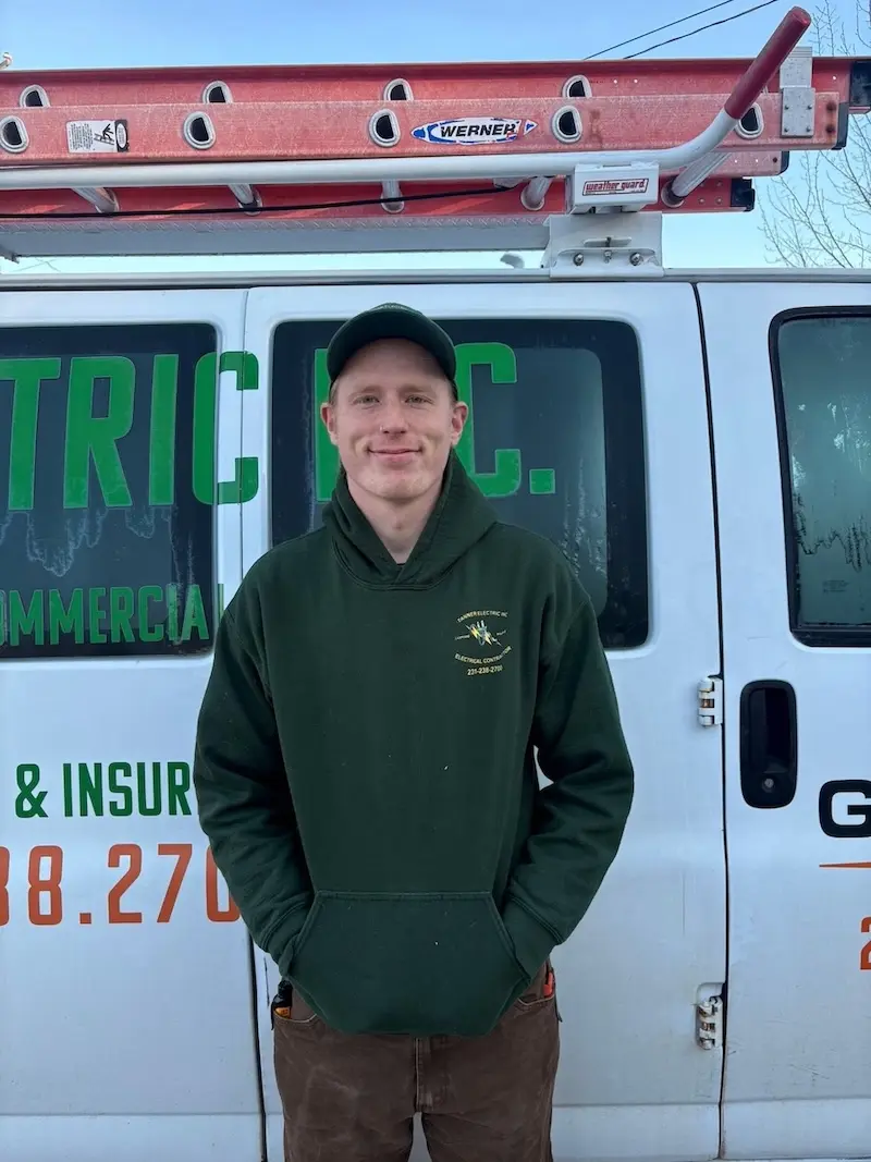 Hunter Brenner, a member of the Tanner Electric Inc. team, wearing a Tanner Electric Inc. shirt and smiling.