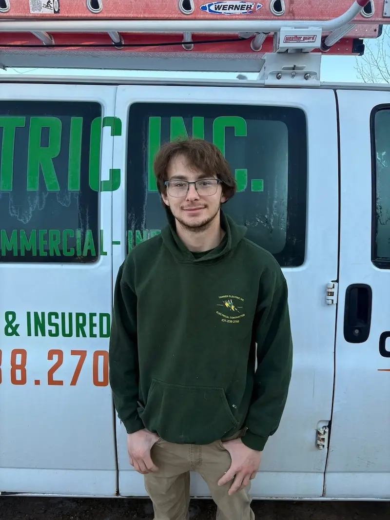 Julian Asposito, a member of the Tanner Electric Inc. team, wearing a Tanner Electric Inc. shirt and smiling.