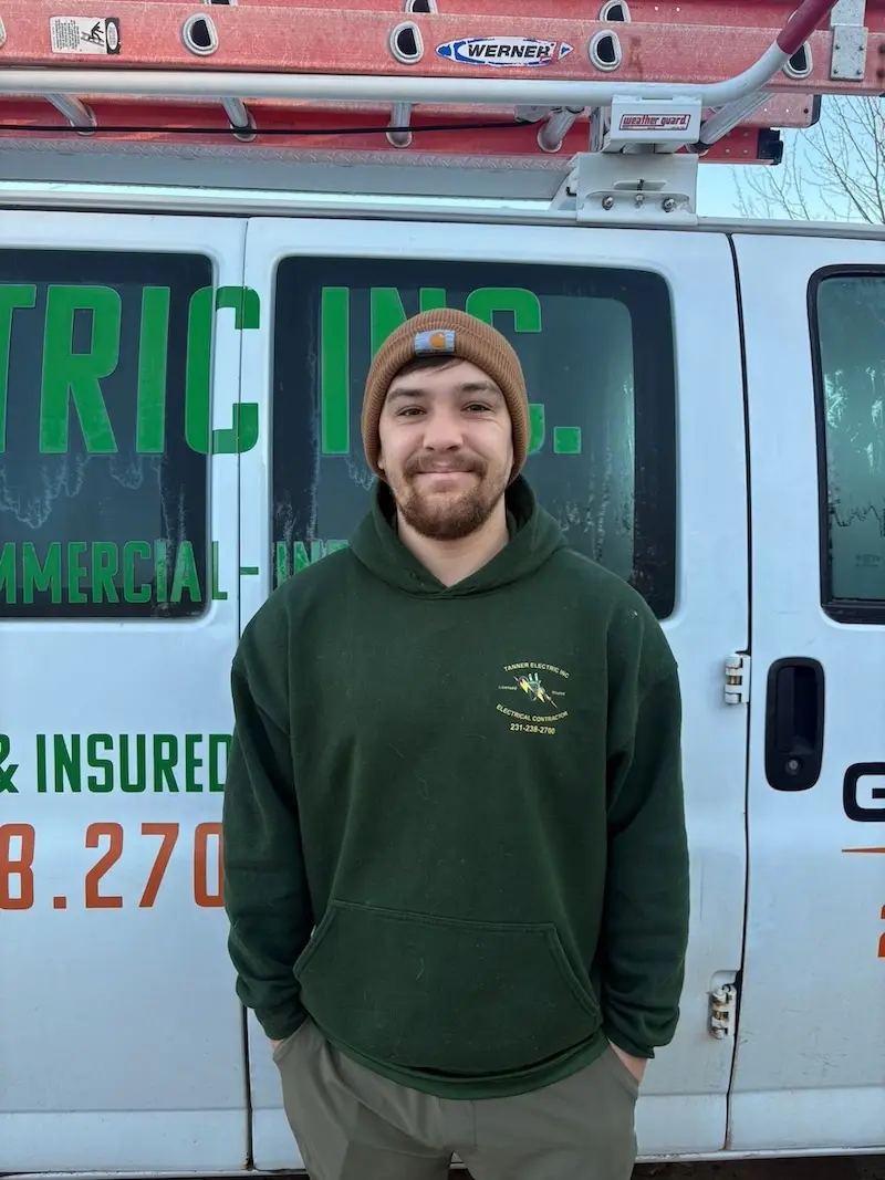 Taylor Tanner, a member of the Tanner Electric Inc. team, wearing a Tanner Electric Inc. shirt and smiling.